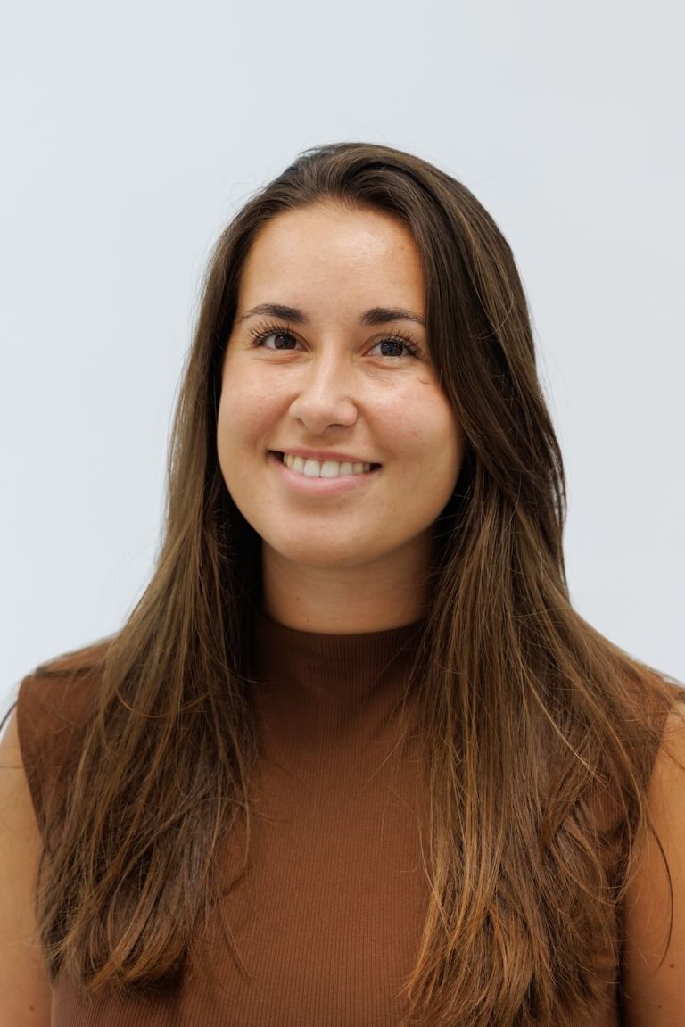 Portretfoto van Fleur Houtepen, een tandarts, die warm glimlacht in een professionele omgeving.